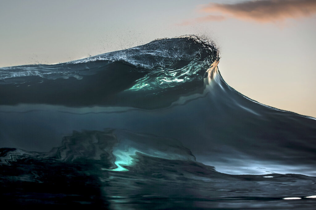 A shot of a wave crashing down into the ocean in the clear waters of Teahupoo.